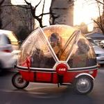 beijing_china_-_a_woman_and_her_son_sit_in_the_capsule_of_an_electric_tricycle_as_they_drive_along_a_main_road.jpg